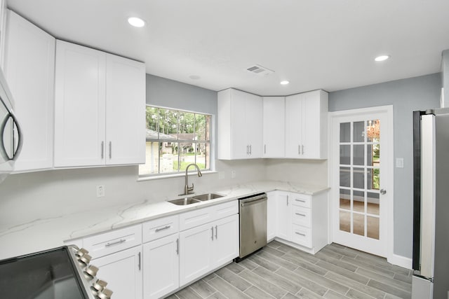 kitchen featuring white cabinets, sink, light hardwood / wood-style flooring, stainless steel appliances, and light stone countertops