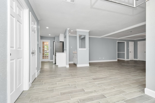 unfurnished living room with a textured ceiling, light hardwood / wood-style floors, and ornamental molding