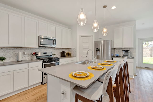 kitchen featuring light hardwood / wood-style floors, white cabinetry, an island with sink, stainless steel appliances, and sink