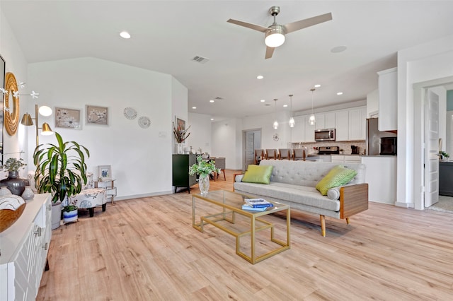 living room with ceiling fan, light wood-type flooring, and vaulted ceiling