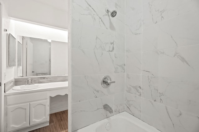 bathroom featuring hardwood / wood-style floors, tiled shower / bath, and vanity