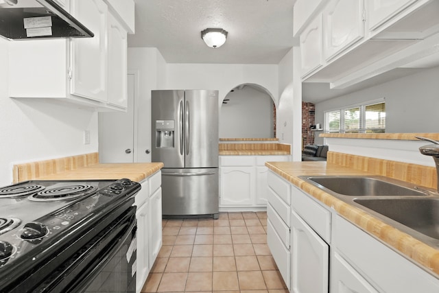 kitchen featuring electric range, light tile patterned flooring, sink, white cabinets, and stainless steel fridge