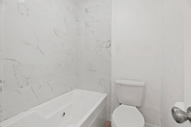 bathroom with a tub to relax in and toilet