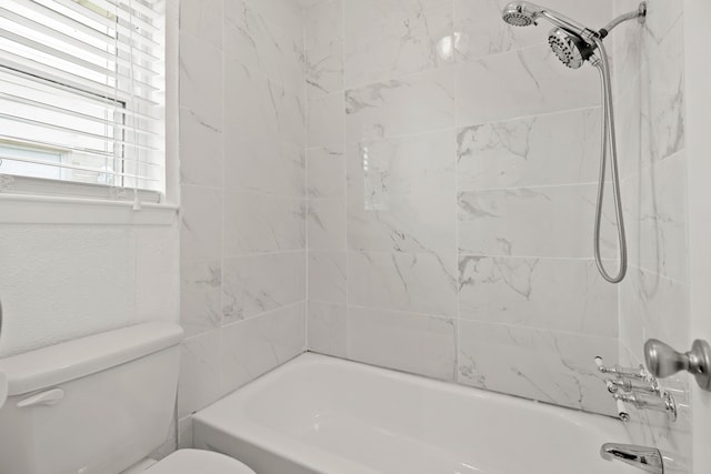 bathroom with tiled shower / bath combo and toilet