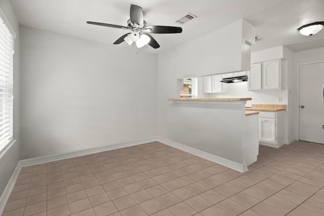 kitchen with kitchen peninsula, white cabinetry, ceiling fan, and light tile patterned floors