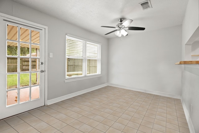 spare room with ceiling fan, a textured ceiling, and light tile patterned floors