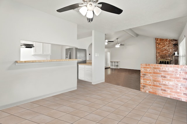 unfurnished living room featuring light wood-type flooring, a fireplace, lofted ceiling with beams, and ceiling fan