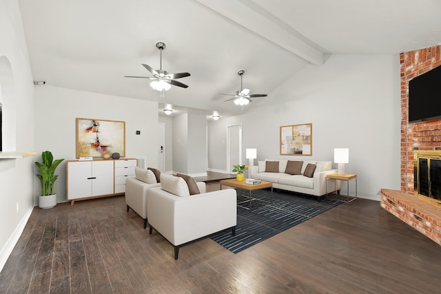 living room with vaulted ceiling with beams, ceiling fan, dark wood-type flooring, and a brick fireplace