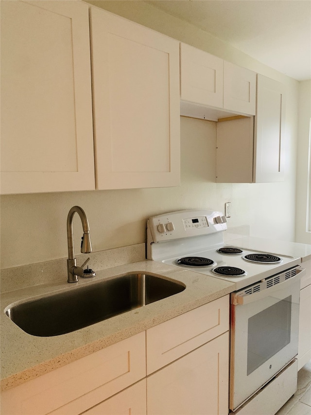 kitchen with white cabinets, white electric range oven, sink, and light stone counters