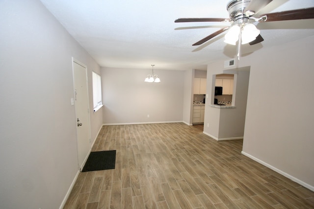 empty room featuring ceiling fan with notable chandelier and light wood-type flooring