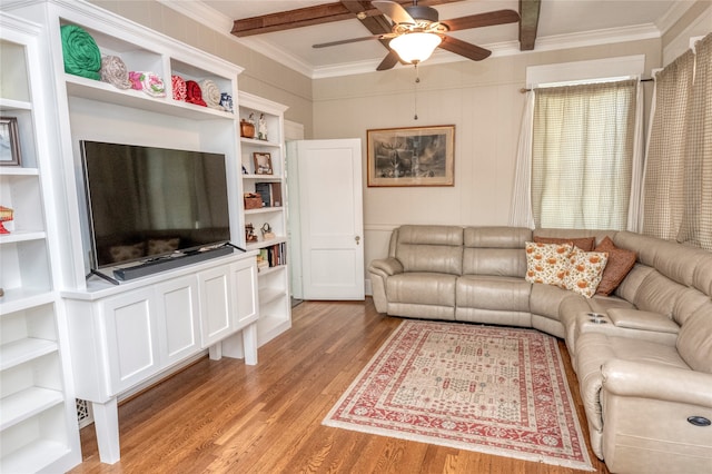 living room featuring ceiling fan, ornamental molding, beam ceiling, wooden walls, and light hardwood / wood-style floors