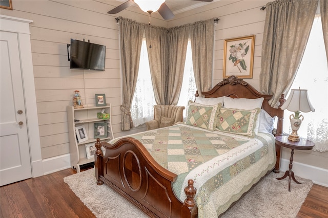 bedroom featuring wood walls, dark hardwood / wood-style flooring, and ceiling fan