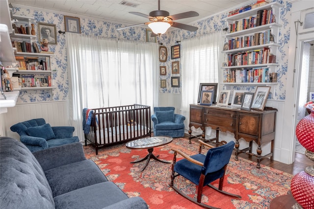 living room with ornamental molding, wood-type flooring, and ceiling fan