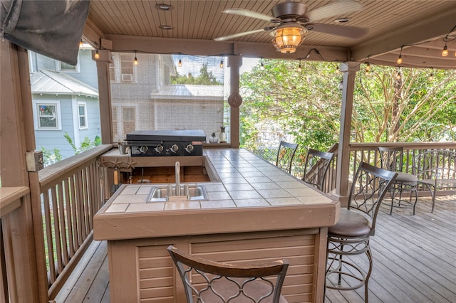 wooden terrace featuring a wet bar, ceiling fan, and a grill