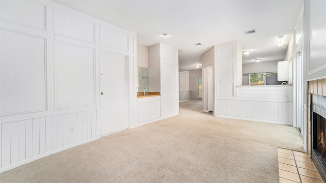 unfurnished living room with light colored carpet and a fireplace