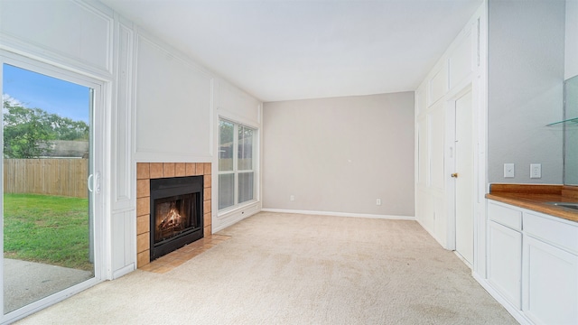 unfurnished living room featuring light carpet, plenty of natural light, and a tile fireplace