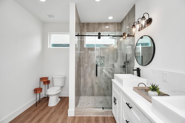 bathroom with hardwood / wood-style floors, vanity, toilet, and a shower with shower door