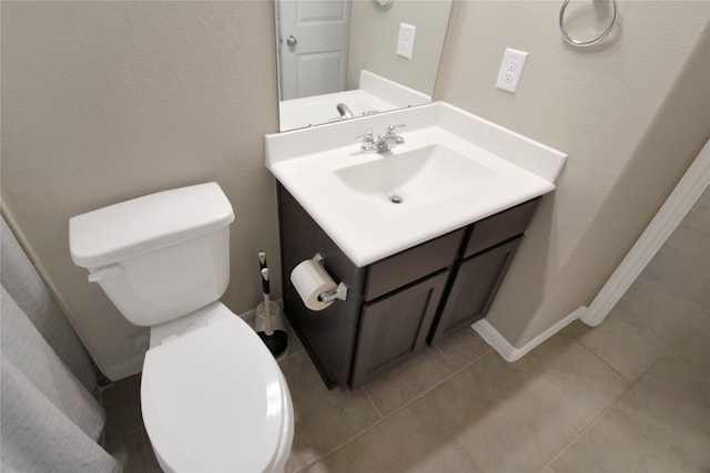 bathroom with toilet, vanity, and tile patterned flooring