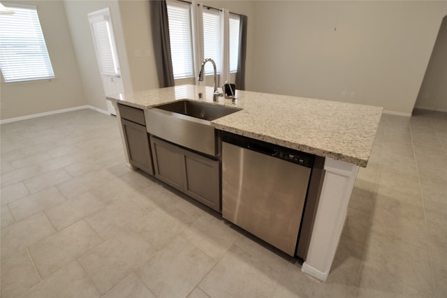 kitchen featuring light stone countertops, stainless steel dishwasher, sink, and a wealth of natural light