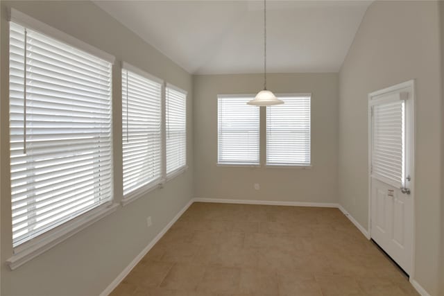 unfurnished dining area featuring vaulted ceiling and light tile patterned floors