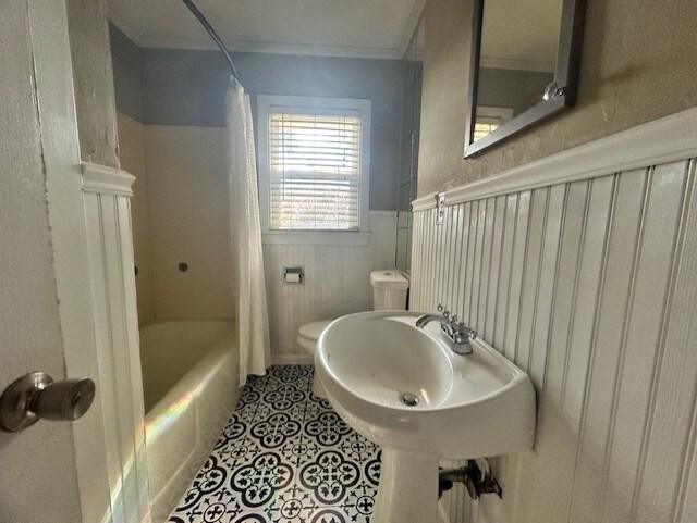 515 Breezy Ln, Wharton, TX 77488 - bathroom featuring toilet, tile patterned flooring, a wainscoted wall, shower / tub combo, and crown molding