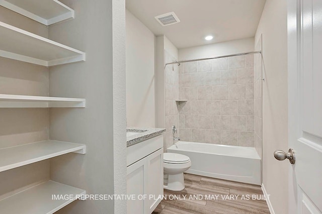 full bathroom featuring tiled shower / bath combo, vanity, hardwood / wood-style flooring, and toilet