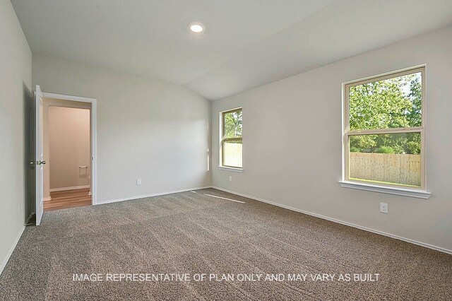 carpeted spare room featuring vaulted ceiling