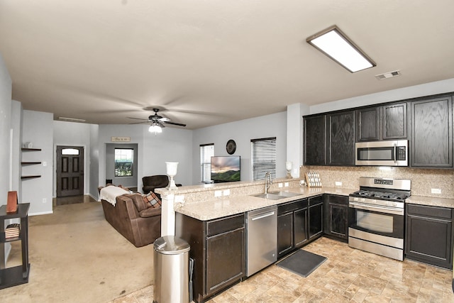 kitchen featuring light stone counters, sink, kitchen peninsula, stainless steel appliances, and ceiling fan