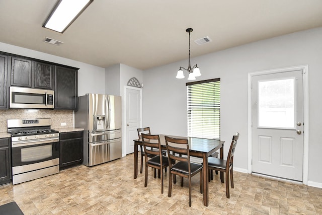 kitchen featuring hanging light fixtures, backsplash, light stone countertops, stainless steel appliances, and a notable chandelier