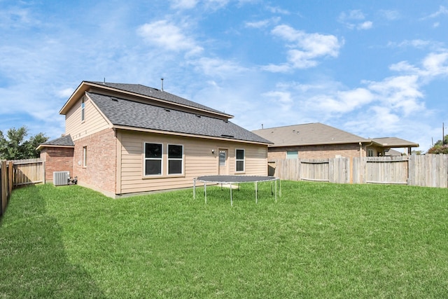 back of property featuring a lawn, cooling unit, and a trampoline