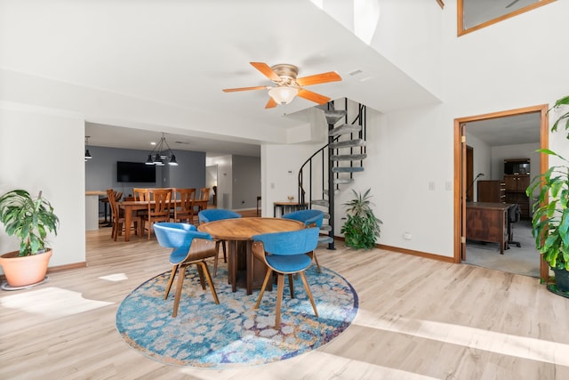 dining space featuring light wood-type flooring and ceiling fan with notable chandelier