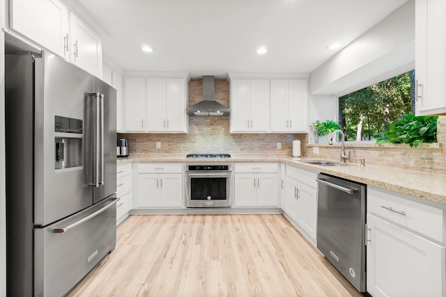 kitchen with wall chimney exhaust hood, white cabinetry, and stainless steel appliances