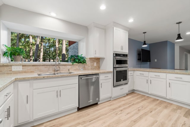 kitchen with tasteful backsplash, sink, stainless steel appliances, pendant lighting, and white cabinets