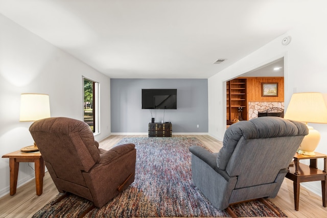 living room featuring a stone fireplace and light hardwood / wood-style floors