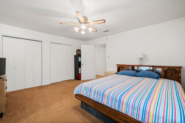 carpeted bedroom featuring two closets and ceiling fan