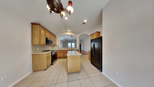 kitchen featuring appliances with stainless steel finishes, a kitchen island, light tile patterned floors, sink, and a notable chandelier