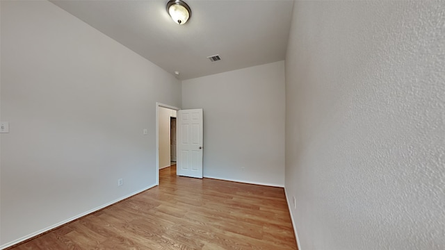 empty room with light wood-type flooring and high vaulted ceiling