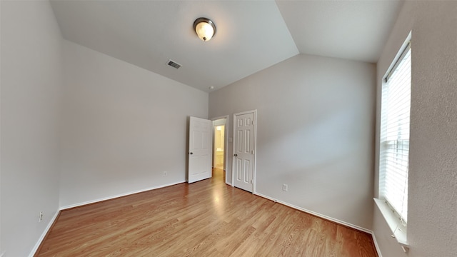 empty room featuring light wood-type flooring and vaulted ceiling