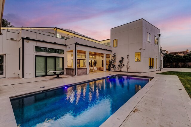 pool at dusk with a patio area