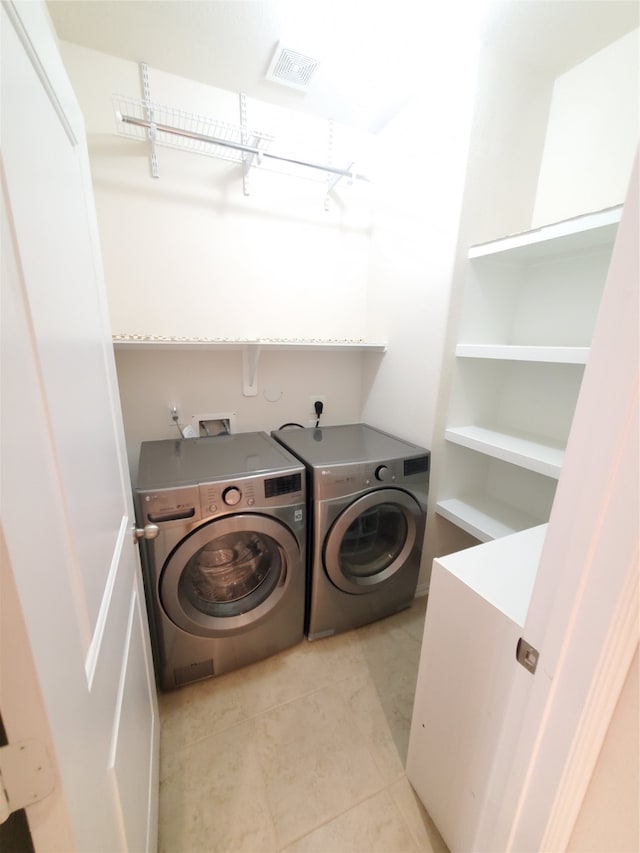 laundry room with independent washer and dryer and light tile patterned floors