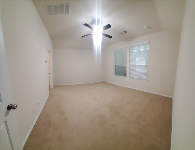 spare room featuring lofted ceiling, ceiling fan, and light colored carpet