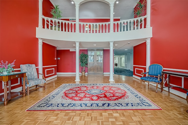 entryway with parquet floors, a towering ceiling, and ornate columns