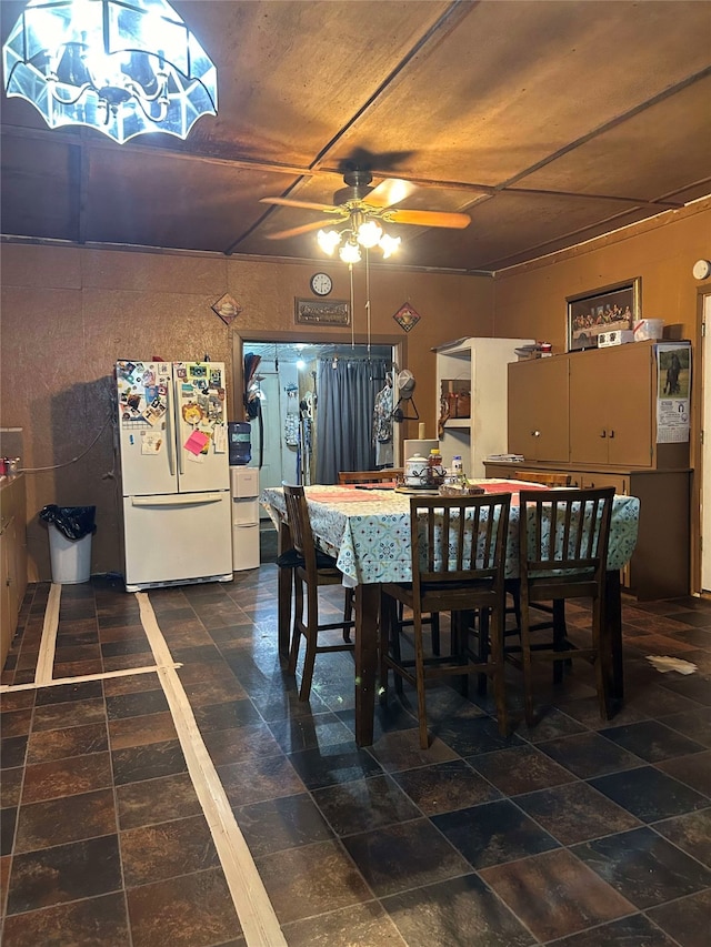 dining space featuring ceiling fan with notable chandelier