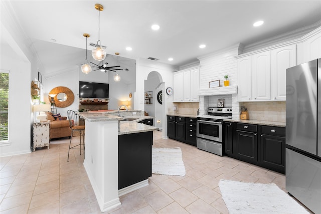 kitchen featuring white cabinets, tasteful backsplash, a center island with sink, appliances with stainless steel finishes, and a kitchen bar