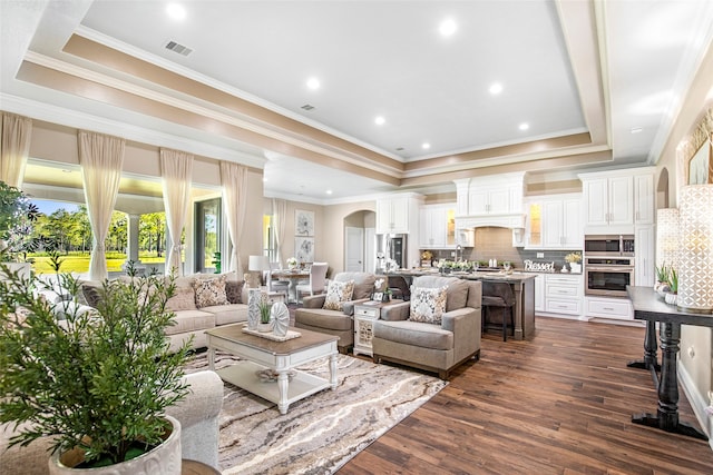 living room with ornamental molding, a raised ceiling, and dark wood-type flooring