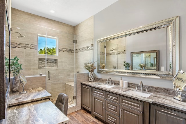 bathroom with wood-type flooring, a shower with door, and vanity