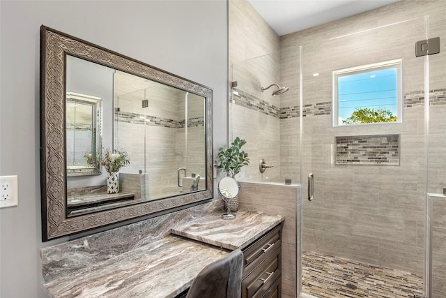 bathroom featuring a shower with shower door and vanity