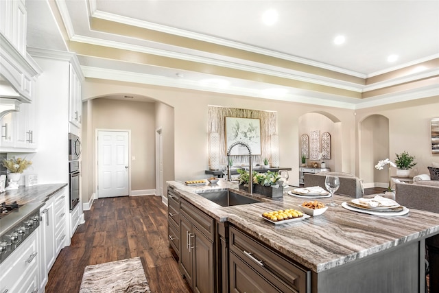 kitchen featuring appliances with stainless steel finishes, white cabinetry, an island with sink, dark hardwood / wood-style flooring, and dark brown cabinetry