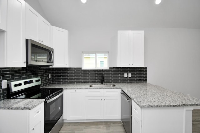 kitchen with kitchen peninsula, light wood-type flooring, stainless steel appliances, sink, and white cabinets