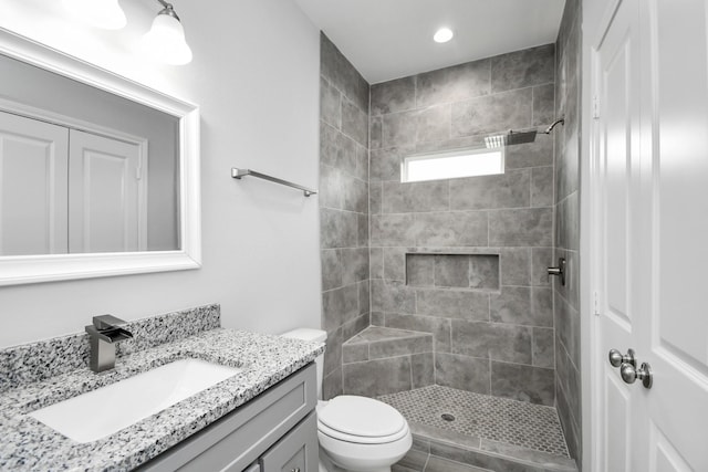 bathroom featuring tiled shower, vanity, and toilet